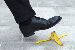 a man's foot in a dress shoe, about to step on a banana peel