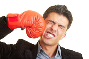 man punching himself in the face, wearing a boxing glove
